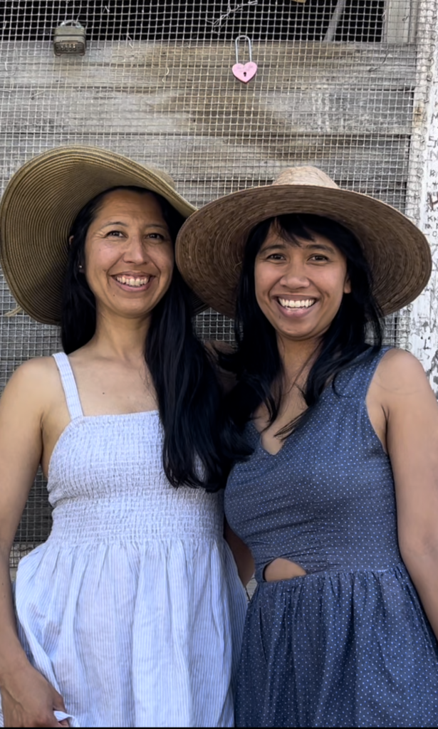 Angel and Jelly, donning hats and blue sundresses, smile at the camera.
