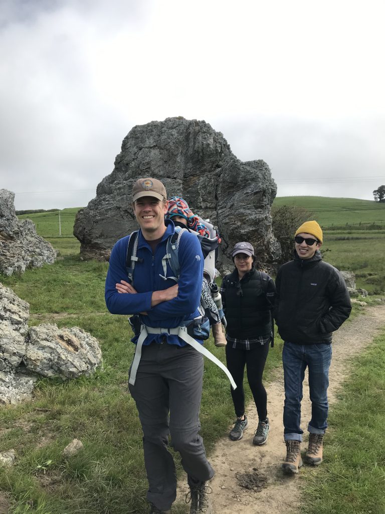 A group of three adults with one child in an osprey poco pack in Point Reyes