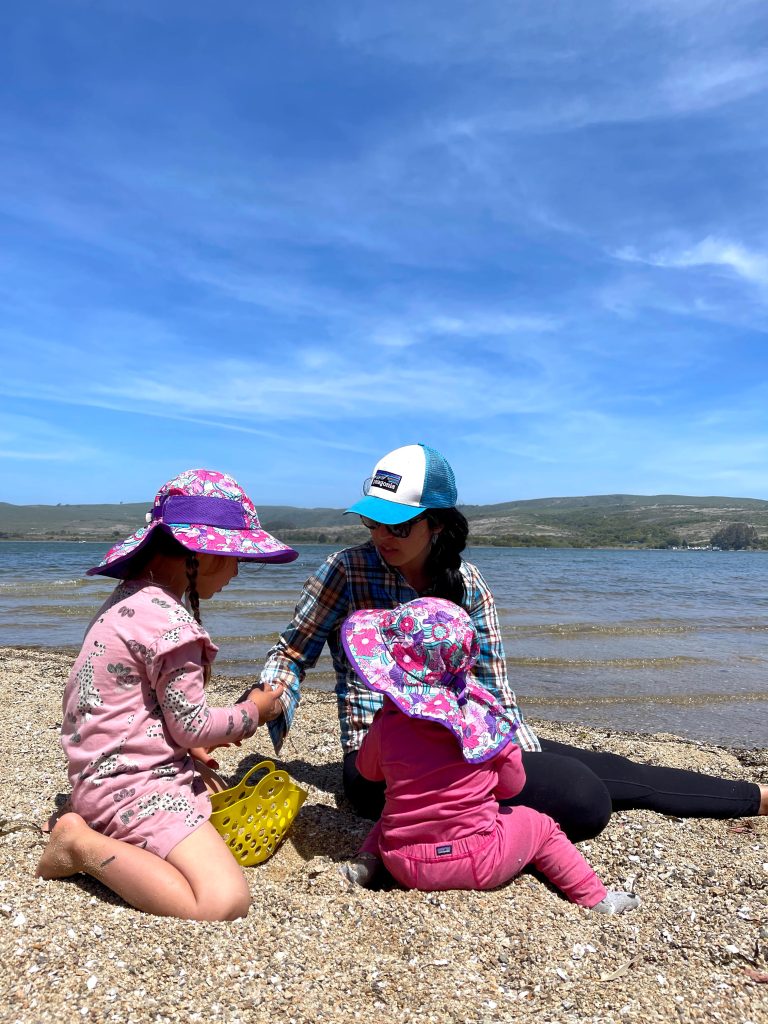 An adult and two kids with hats on the beach in Inverness near Point Reyes National Seashore in California